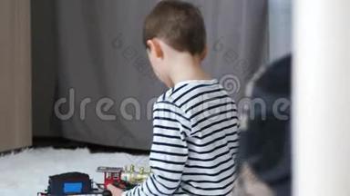 一个学前男孩在一个房间里玩耍，坐在地板上。 一个孩子玩铁路和火车头。 儿童`
